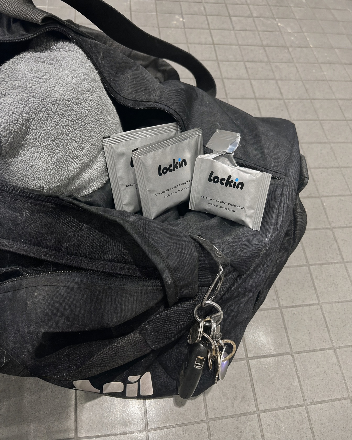Foil sachets in the side pocket of a gym bag next to a towel and keys